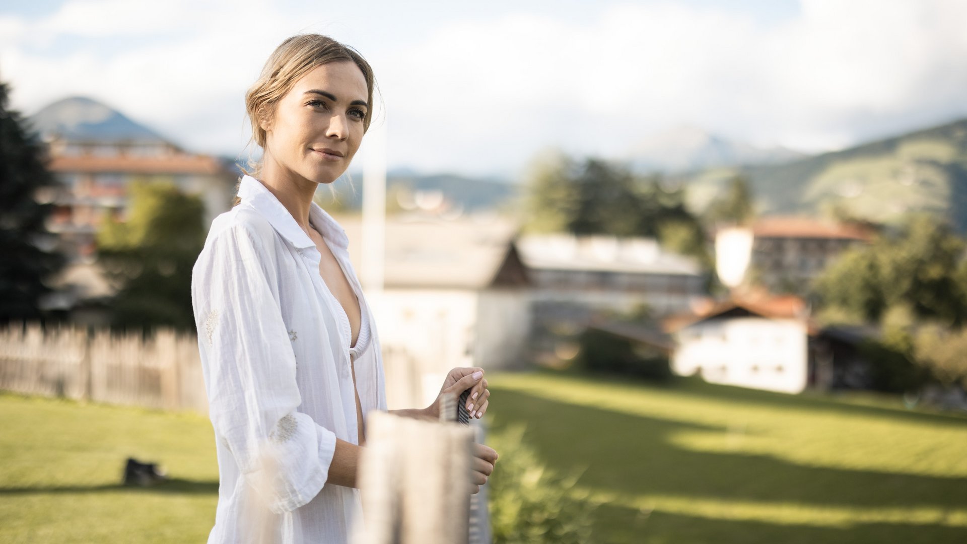 Ihr Hotel in Natz-Schabs bei Brixen, Südtirol Frau in weißem Hemd steht auf einer Wiese mit Bergkulisse im Hintergrund